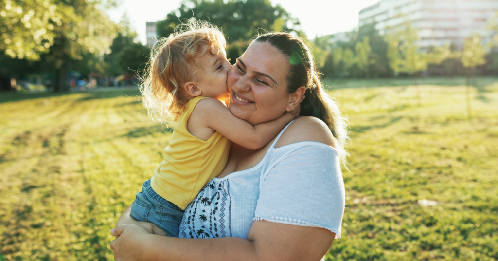 Mama z nadwagą przytula dziecko na łące